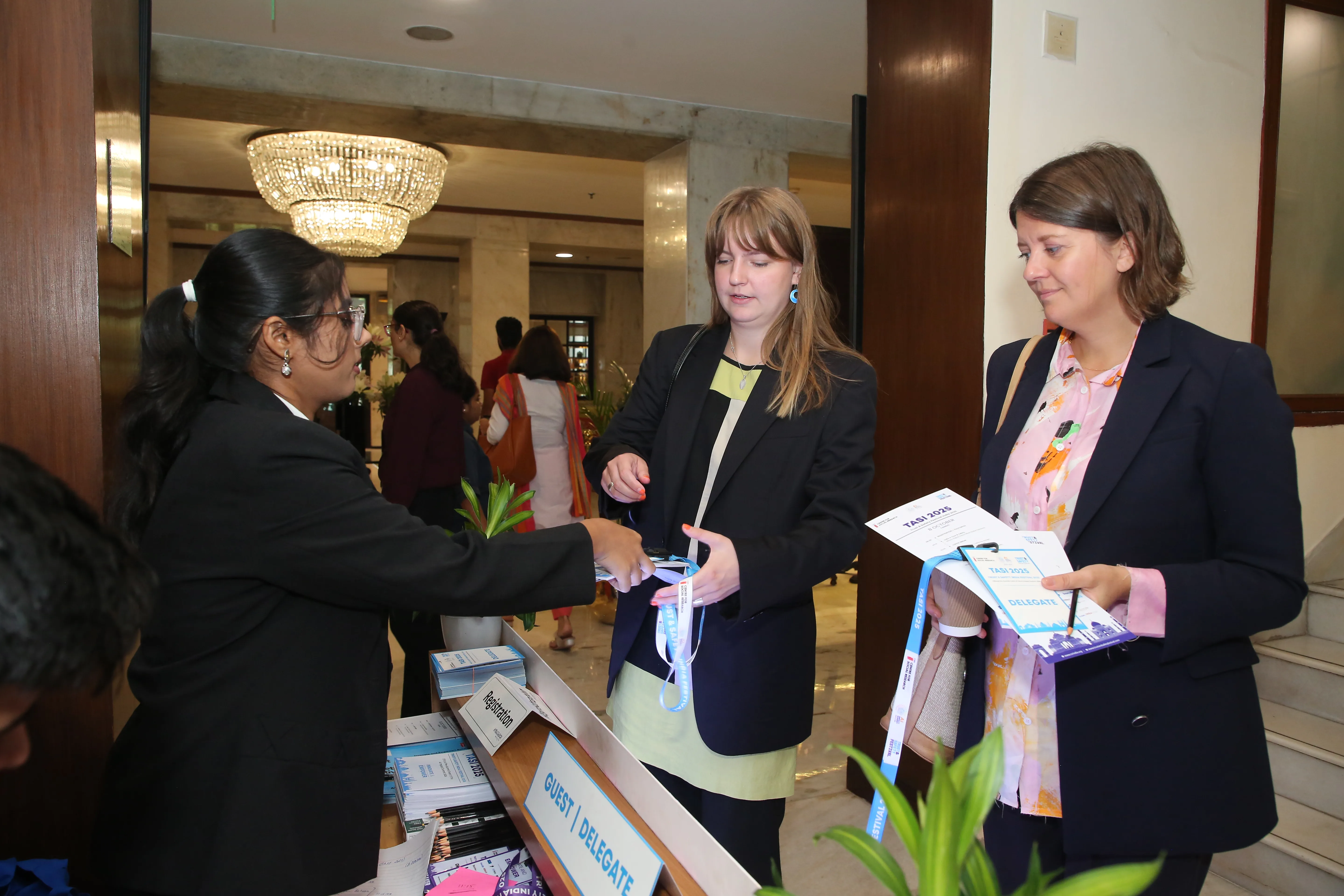 Volunteer handing event materials and badges to guests at TASI